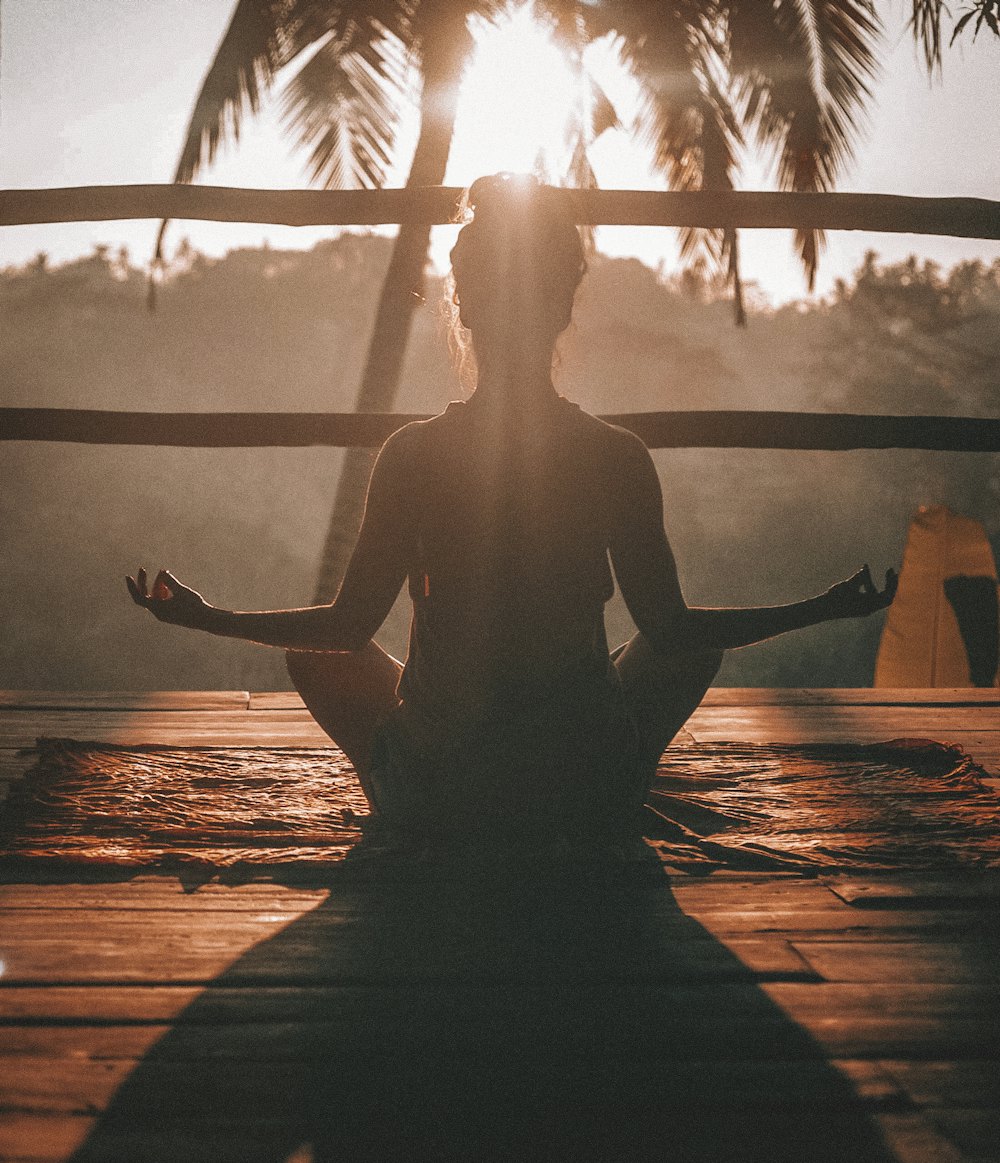 Pessoa praticando meditação Kundalini em posição de lótus ao nascer do sol